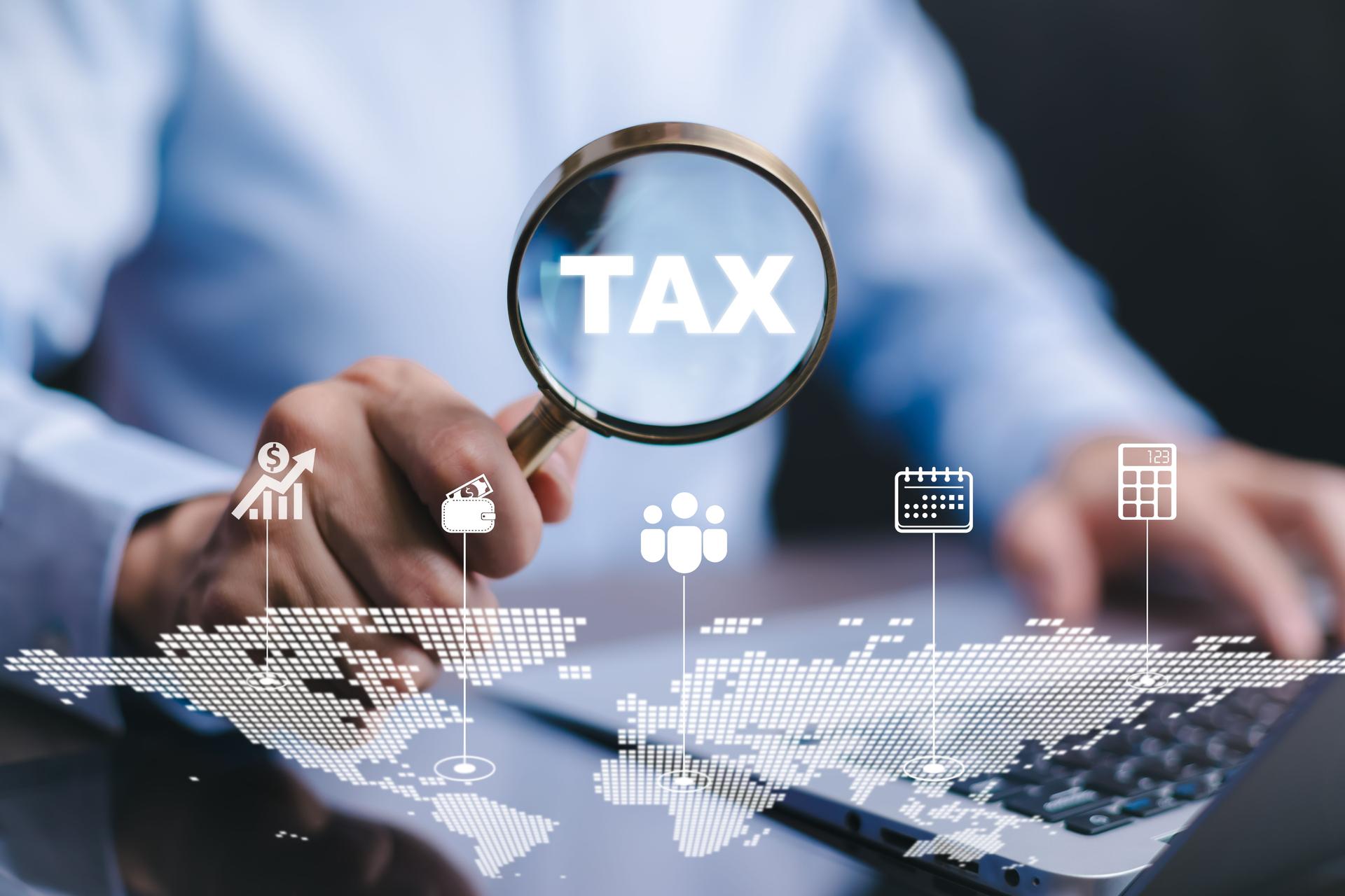 businessman holding a magnifying glass   TAX icon and refund tax of duty taxation business, graphs and chart being demonstrated on the screen media,  tablet pc and selecting tax refund.